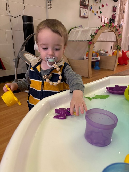 A child exploring the water in a tuff tray.