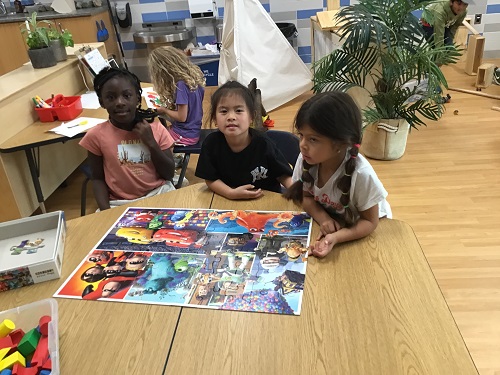 A small group of children showing their completed puzzle they put together.