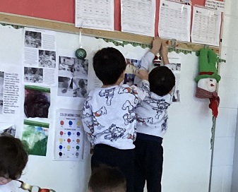 two children putting up christmas decoration on a bulletin board