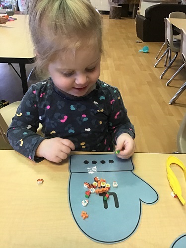Preschool child sorting erasers on mitten