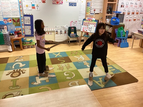 2 children cross country skiing with cardboard skis