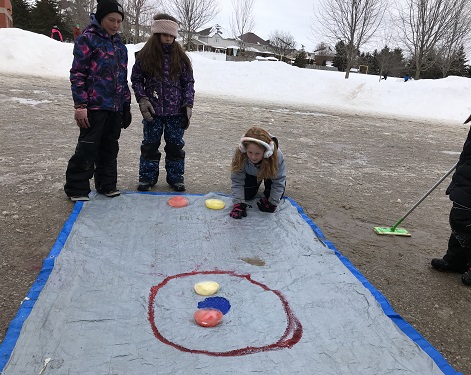 school age children curling with ice rocks and tarp