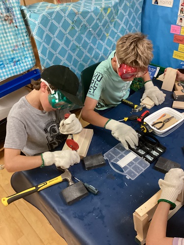 Two children using tools- saw and hammer