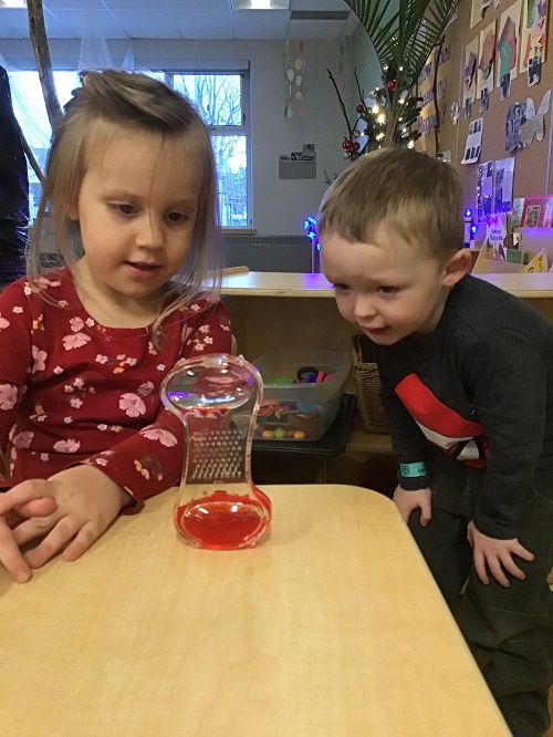 preschool boy and girl watch the colour move from one side of the bottle to the other to help calm their bodies