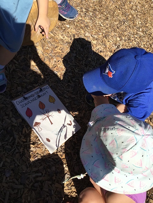 Two preschool children reviewing a fall scavenger hunt list