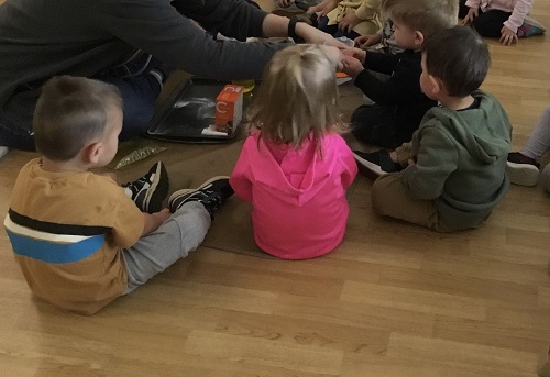 Small group of toddler childen gathered around an educator conducting a science experiment