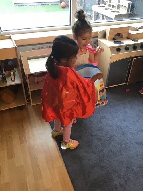 Two preschool girls wearing capes and pretending to be superheroes