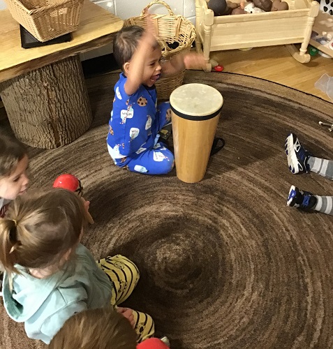 A child drumming on a large drum in front of him