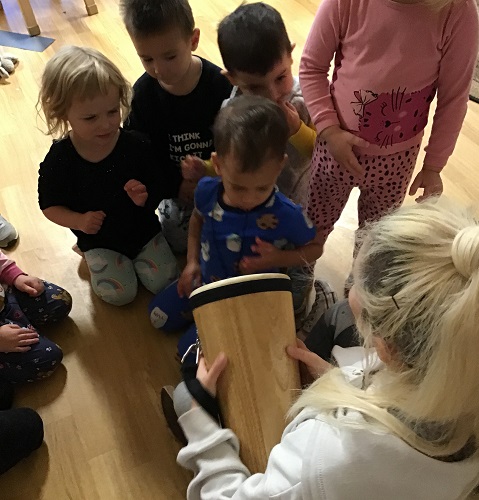 An educator holding a drum the children are taking turns using