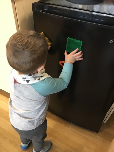 A child putting magnets onto a fridge