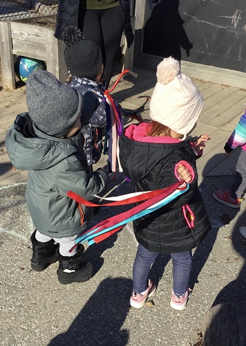 Children outside holding onto ribbons with listening to music