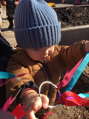 A child examining a ring with ribbons tied to it