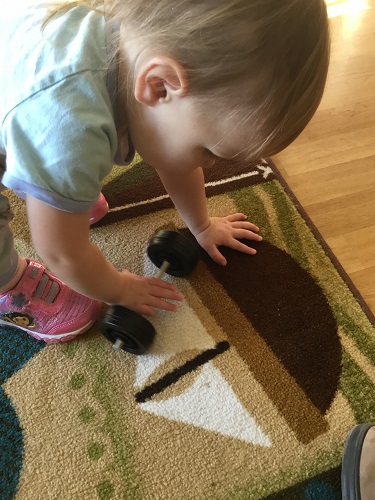 A child pushing small wheels on the carpet