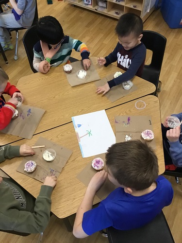 Children sitting around a table eating cupcakes