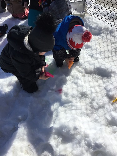 Children outside spraying chalk paint in the snow