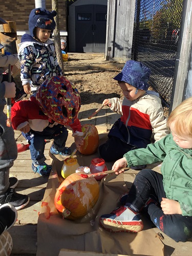 Children outside painting pumpkins