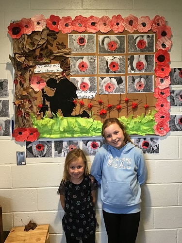 Two children standing in front of a Remembrance Day display