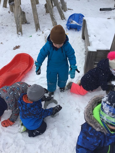 Children filling up a pail with snow