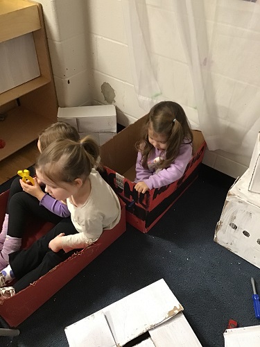 Children sitting in sleigh boxes painted red