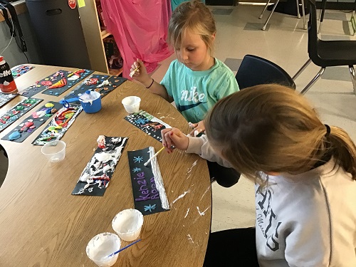 Two children sitting at a table working on crafts