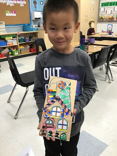 A child showing off his paper bag gingerbread house