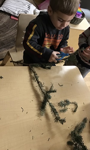 A child sitting at the table cutting a branch