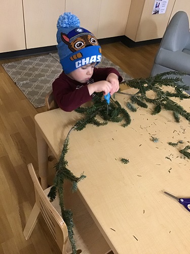 Child sitting at the table cutting branches
