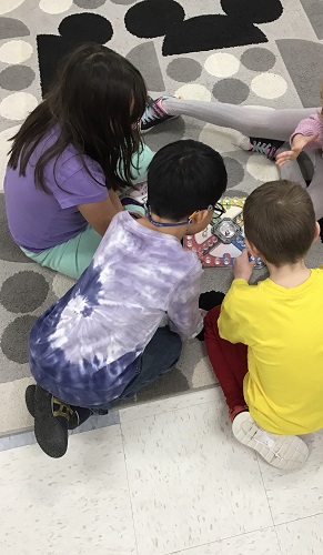 Children on the floor surrounding a board game