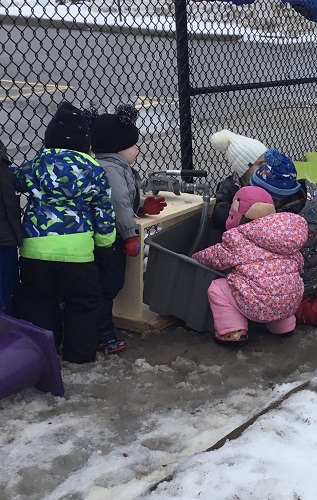 Children outside checking out the new water pump table