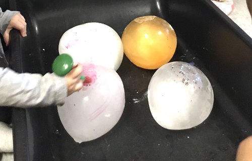 A child's hands touching large frozen balls of ice