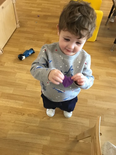 A child showing off a piece of cut tissue paper