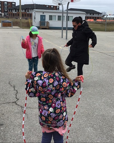Two children skipping with an educator