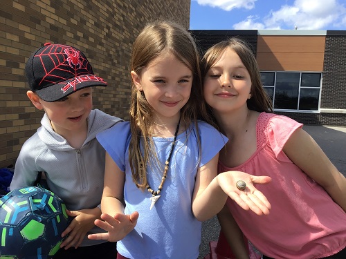 Three children looking at a snail in one child's hand