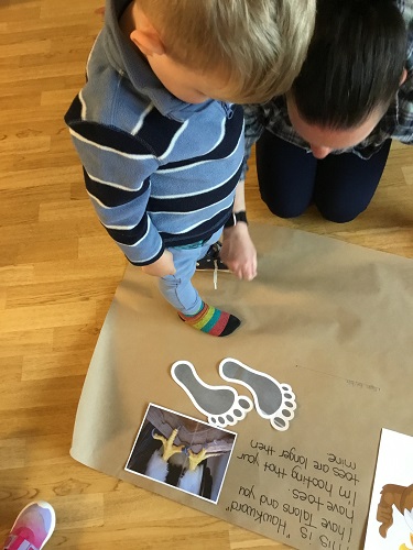 A child standing on a paper while an educator measures his feet