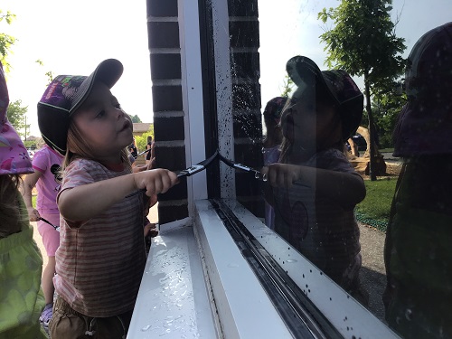 A child painting the window with a paint brush and water