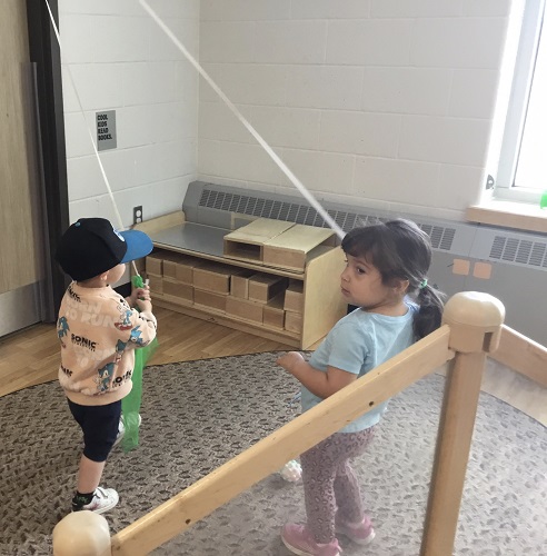 Two children pulling on scarves attached to an elastic