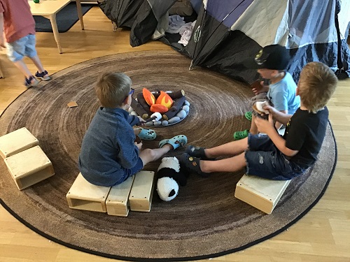 Children sitting on blocks around a pretend camp fire