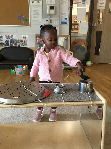 A child standing at a shelf covered in metal pots and pans