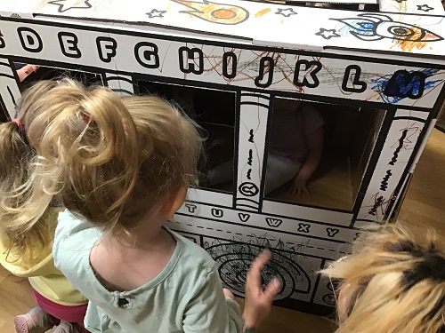 Children colouring on a cardboard bus 