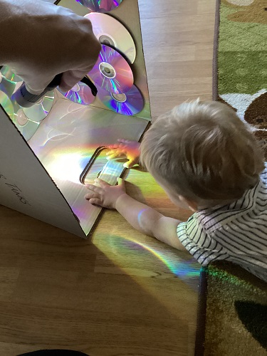 An infant on the floor looking at the reflections on the floor