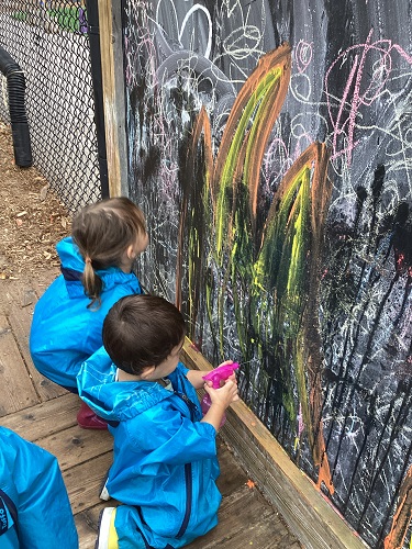Children using spray bottles to squirt water on the chalk board
