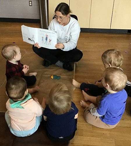 An educator reading a story to a group of infants