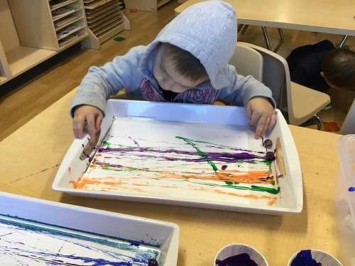 A child at a table doing marble painting