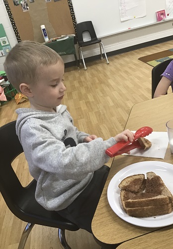 A child using tongs to serve himself snack
