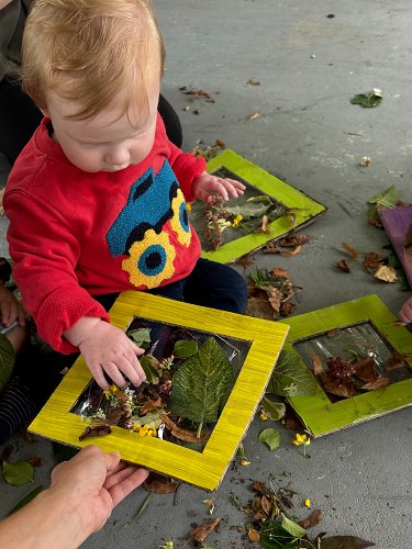 A child sticking nature items to a frame to create artwork