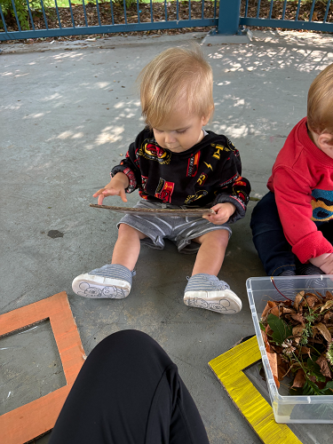 A child sitting on the ground looking at a frame