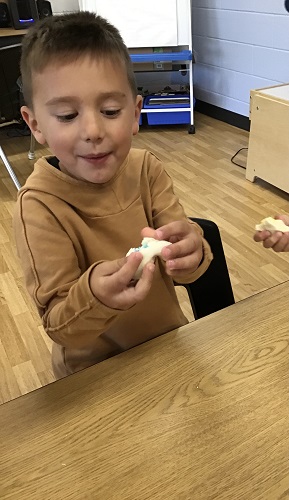 A child sitting at a table with a ball of playdough in their hands