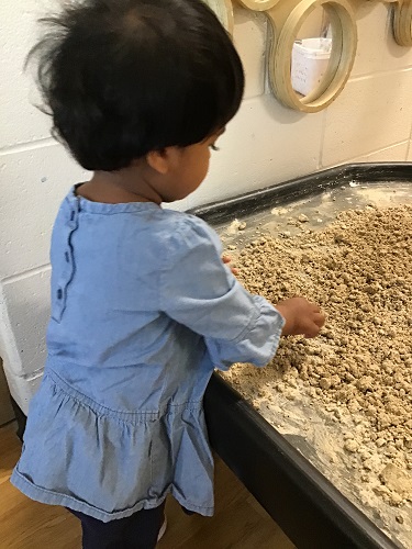 A child playing in sand at the sensory table