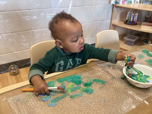 A child using a paint brush to paint on bubble wrap