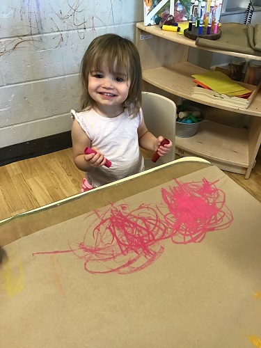 A child drawing on brown paper with chalk paint